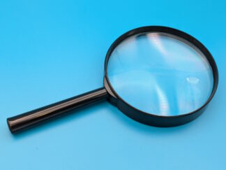 A black magnifying glass laid flat on a blue surface.