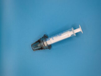 An oral syringe laid on a blue surface. A dark plastic cone sits on the end of the syringe.